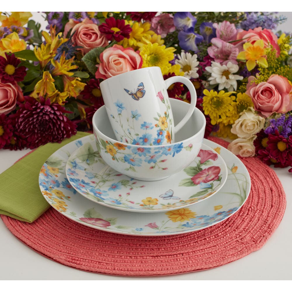 Annabelle floral mug resting in a matching bowl on stacked plates with a colorful bouquet behind.