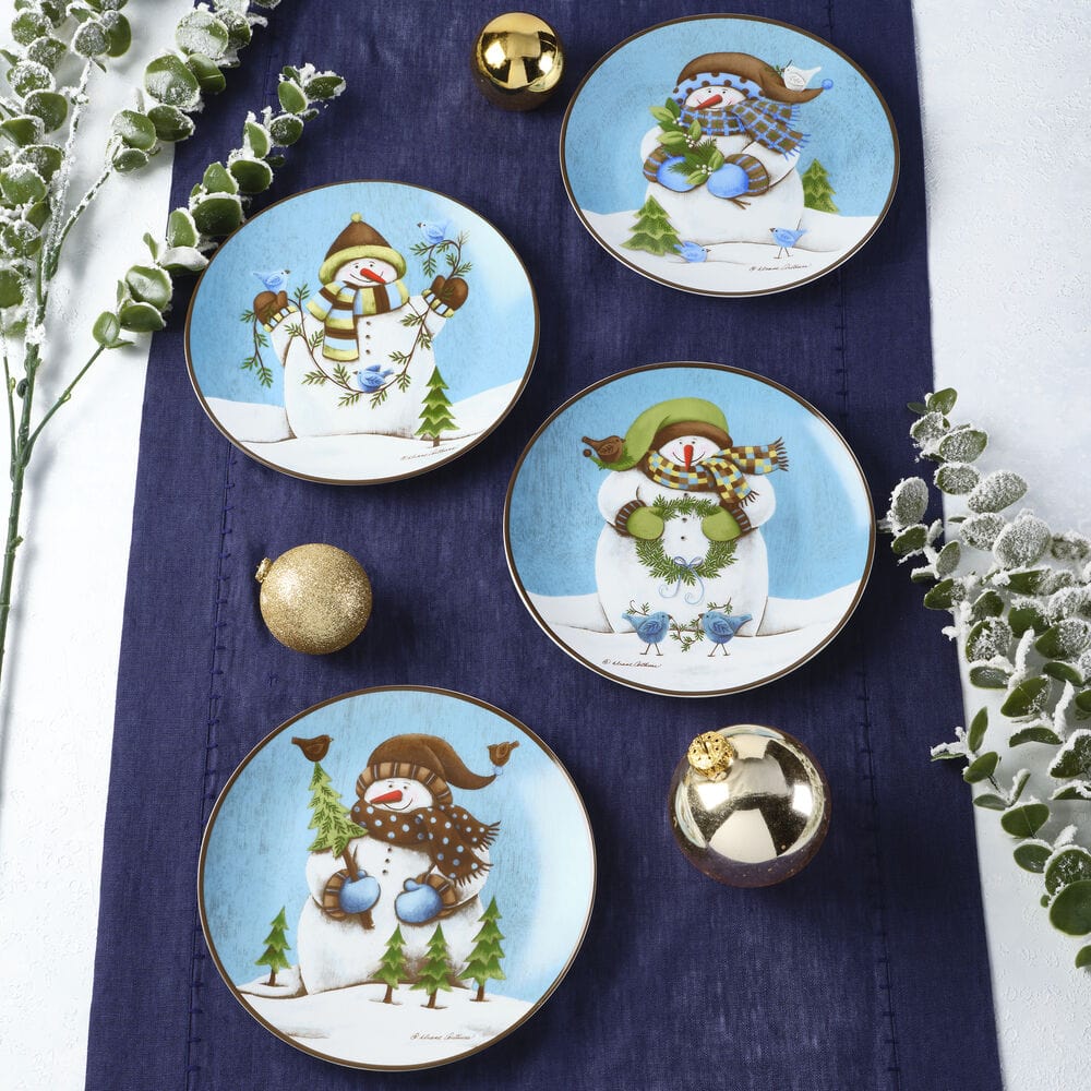 Set of four round salad plates featuring snowman designs on a blue background