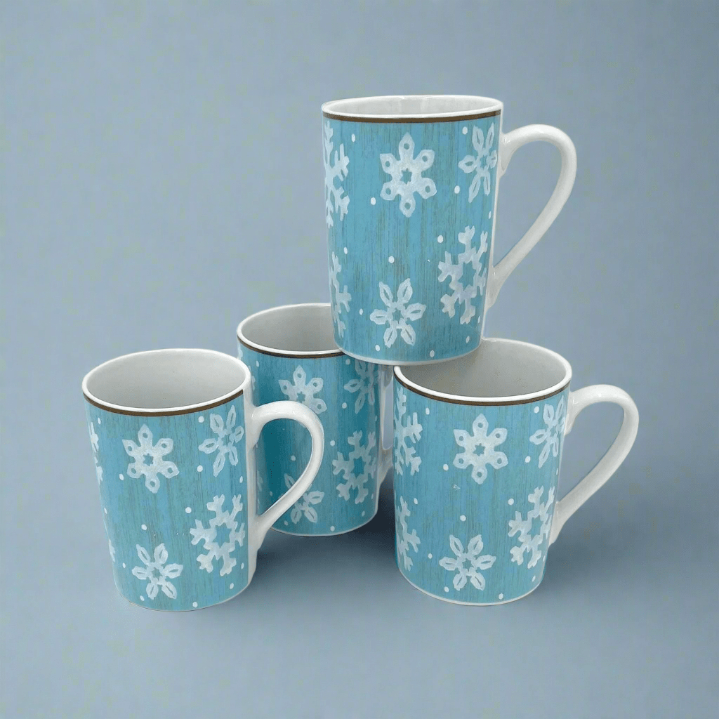 Set of four blue mugs with white snowflake patterns stacked together