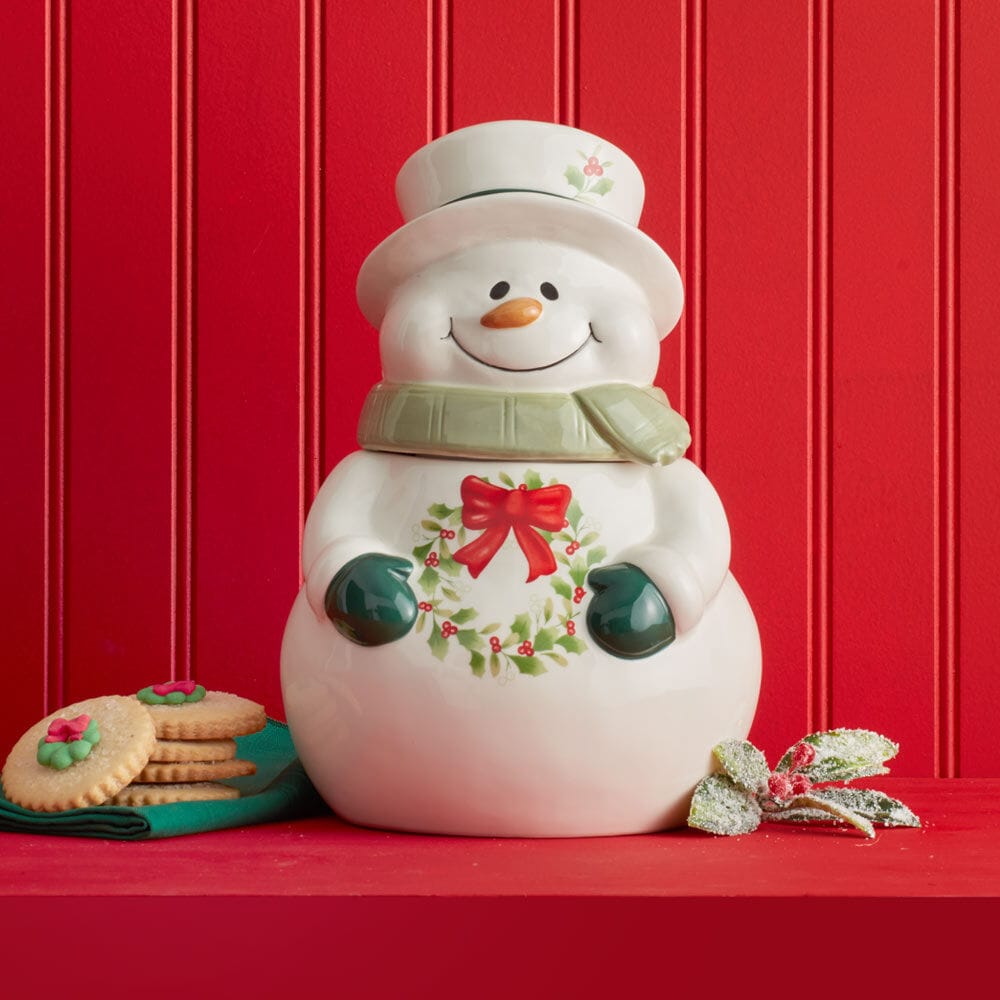 Winterberry Snowman cookie jar on a red backdrop with wreath on belly and cookies nearby.
