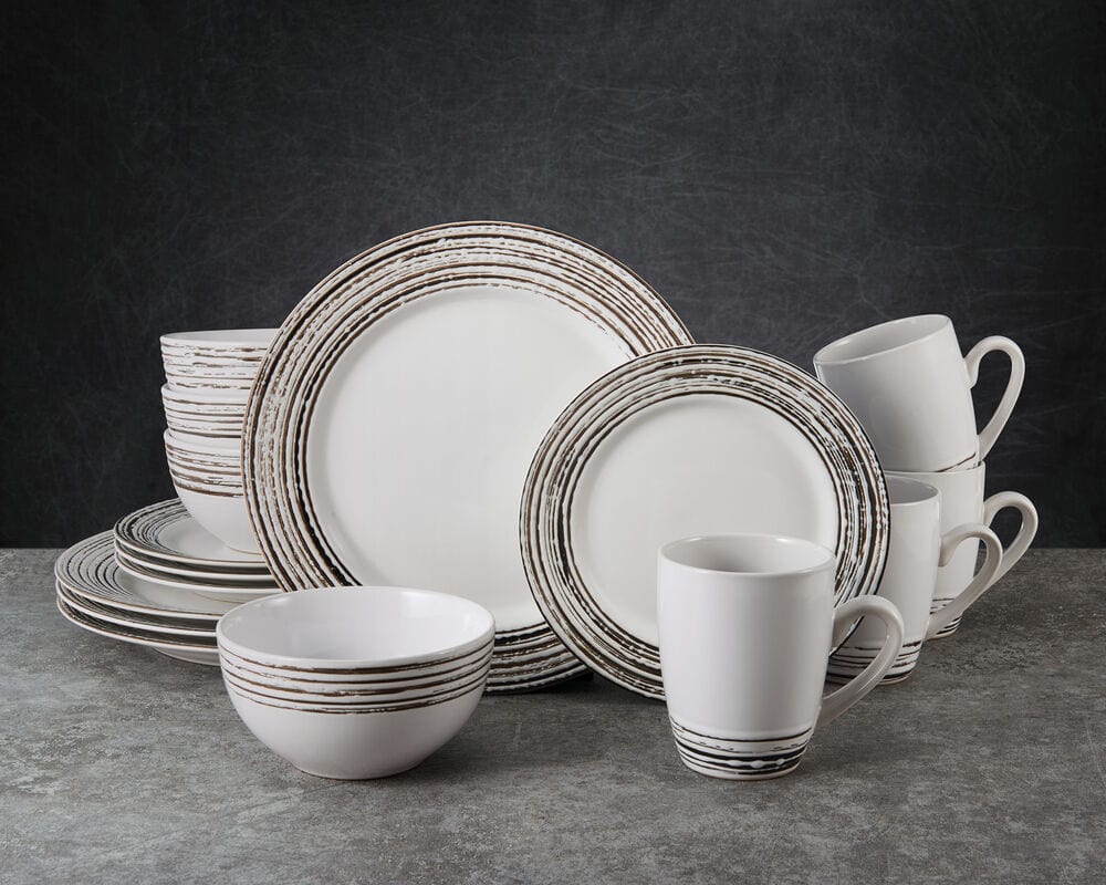 Bryson White 16 piece dinnerware set for four arranged with plates bowls and mugs on a dark textured surface