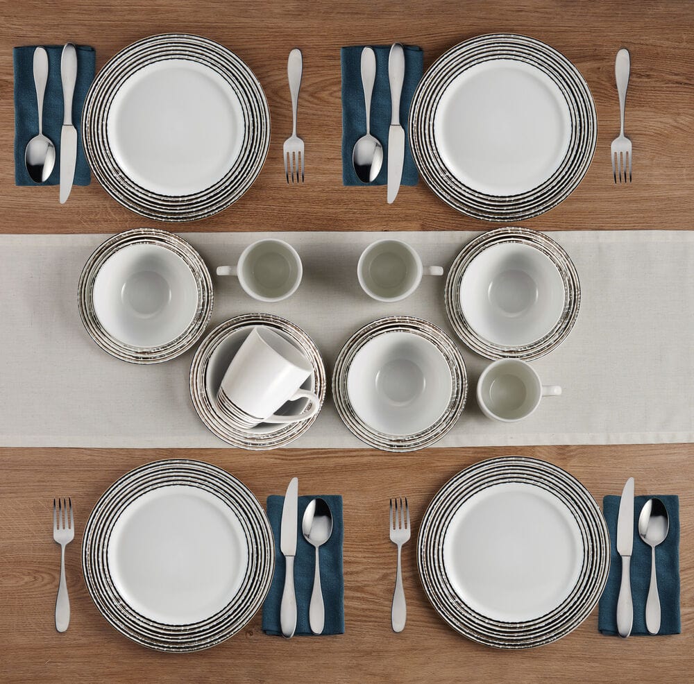 Top view of two place settings with Bryson White striped rim plates blue napkins and mugs on a wooden table