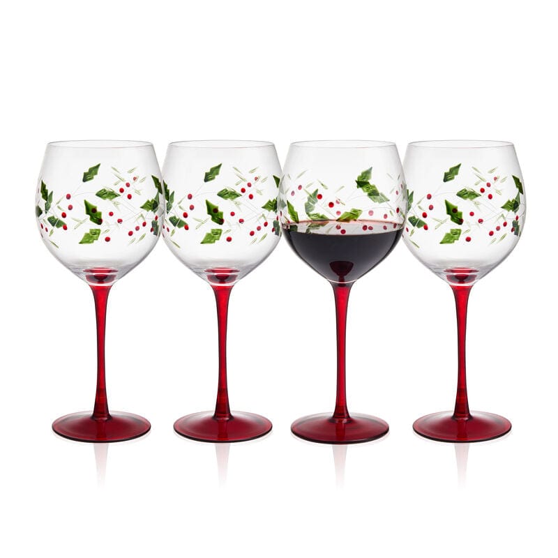 Winterberry set of four hand painted wine goblets with holly motif and red stems, one glass partially filled.