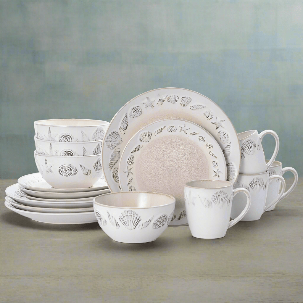 Panama 16 piece dinnerware set for four in white with a sea shell pattern, arranged with plates bowls and mugs.