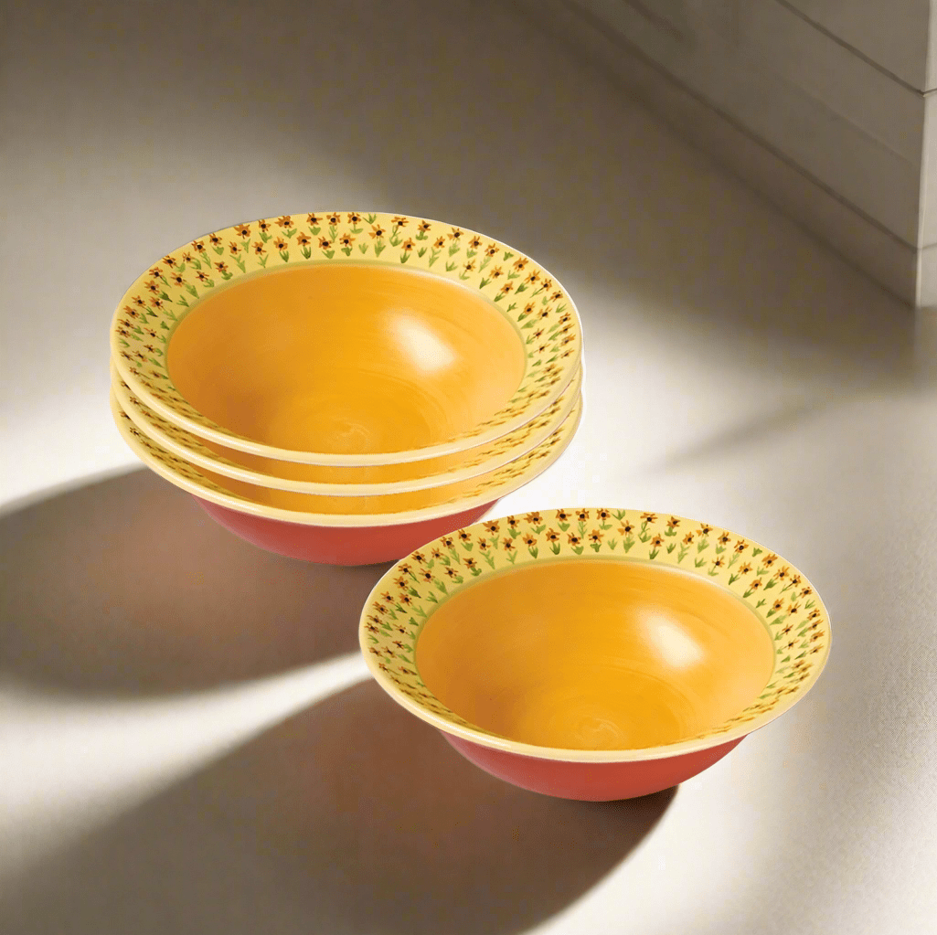 Pistoulet four piece rim soup bowls stacked with yellow interiors, floral rims and pink exteriors.
