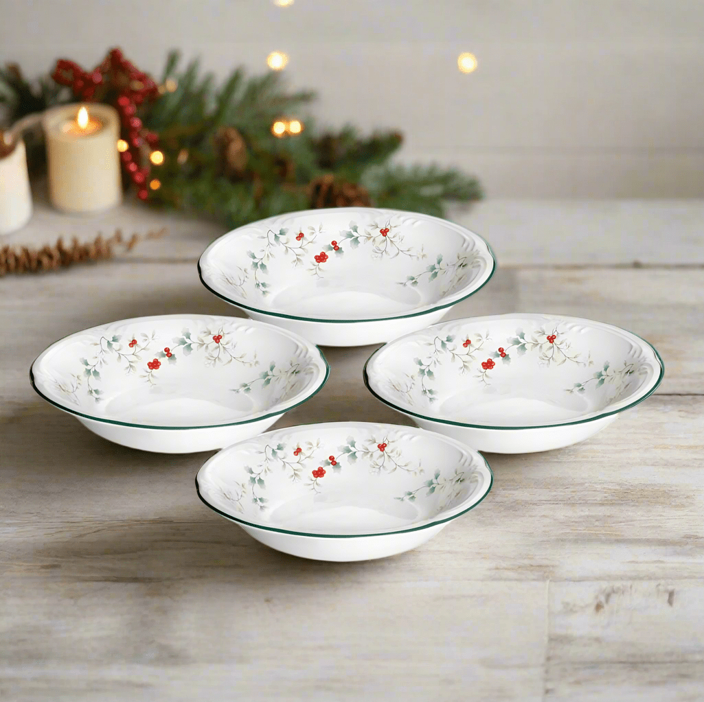 Winterberry set of four white pasta bowls with red holly berries and green leaves on a wooden surface