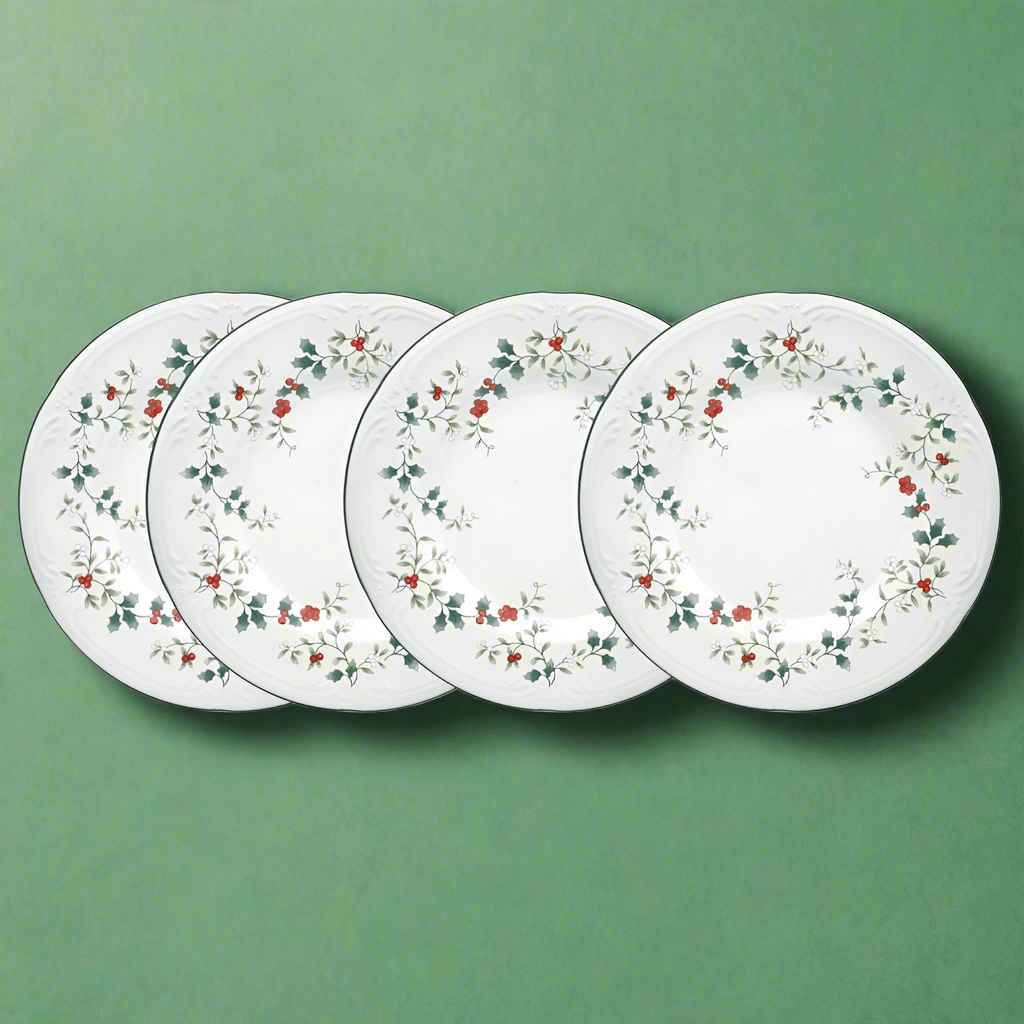 Winterberry Set of 4 luncheon plates with holly border arranged on a green backdrop