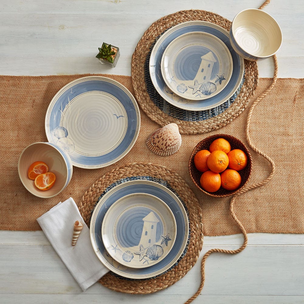 Melamine plastic plates with coastal design on a woven placemat with oranges and shells.