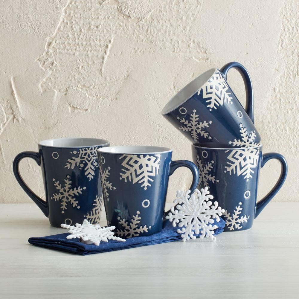 Snow Flurry set of four navy mugs with white snowflake patterns displayed on a light surface.