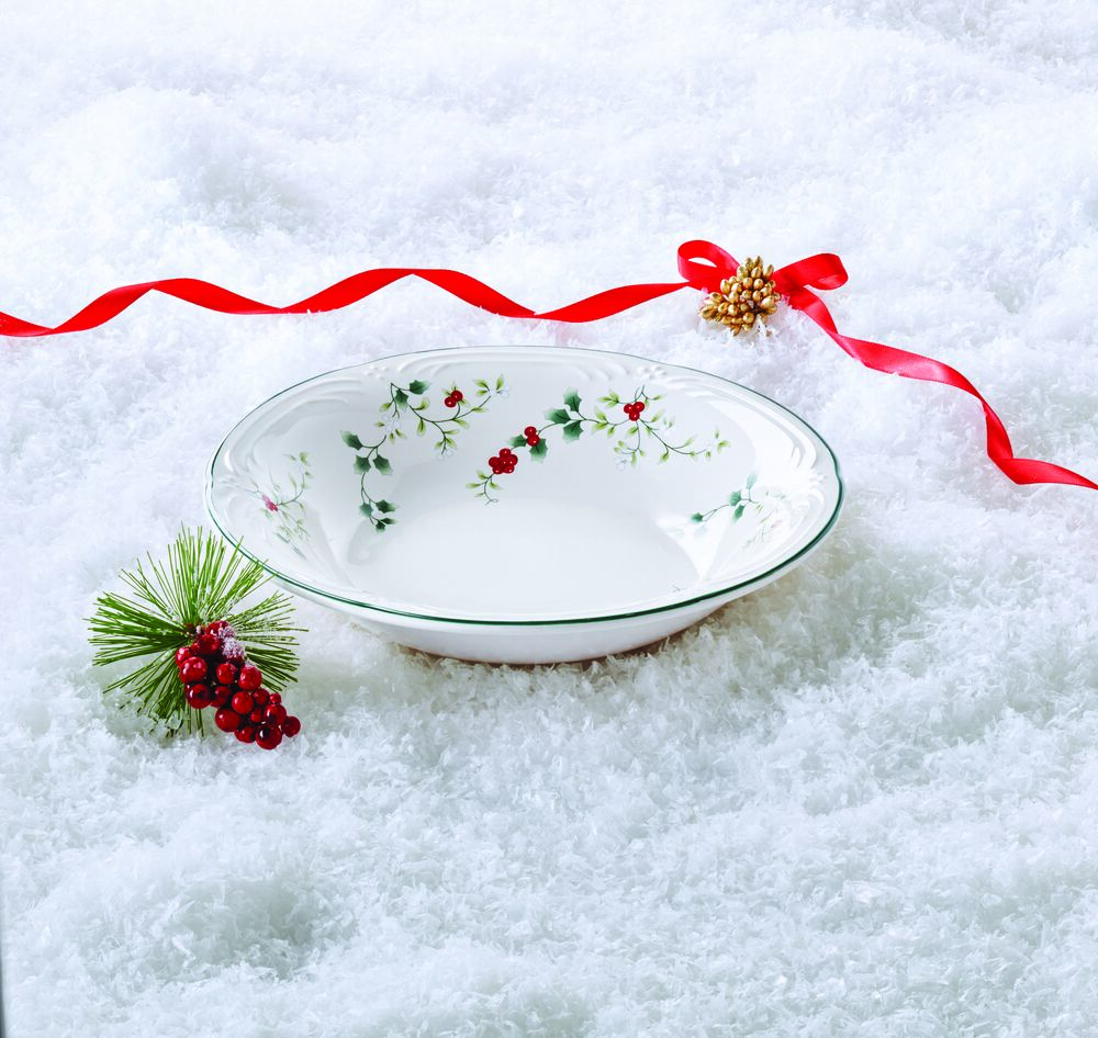 White Winterberry pasta bowl on snow with a red ribbon and pine sprig.