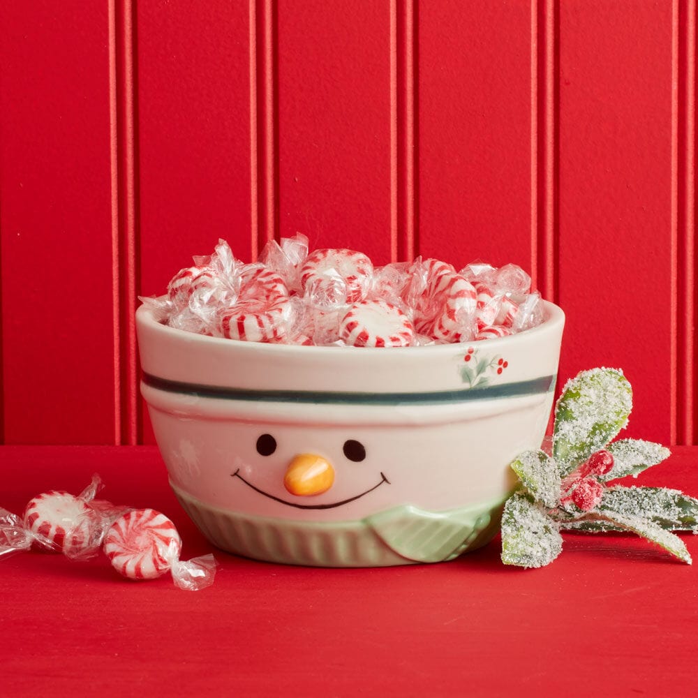 Winterberry Snowman Sculpted Bowl filled with peppermint candies against a red backdrop
