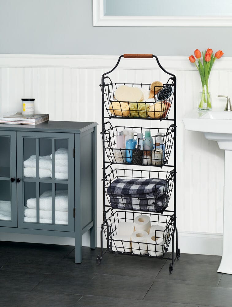 Laguna 4 tier adjustable standing storage rack with four wire baskets filled with towels toiletries and toilet paper beside a blue bathroom cabinet.