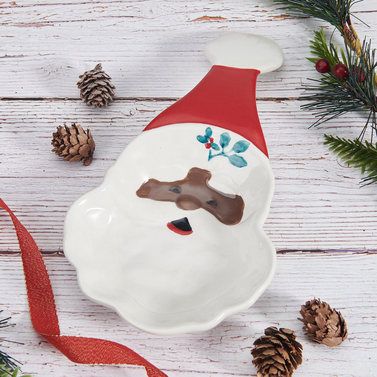 Winterberry African American Jolly Santa spoon rest on a rustic white wooden surface with pine cones and evergreen sprigs.