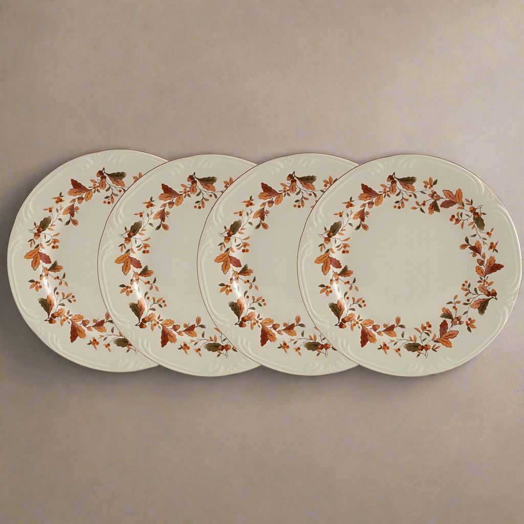 Four Autumn Berry salad plates with a circular floral border laid on a neutral surface
