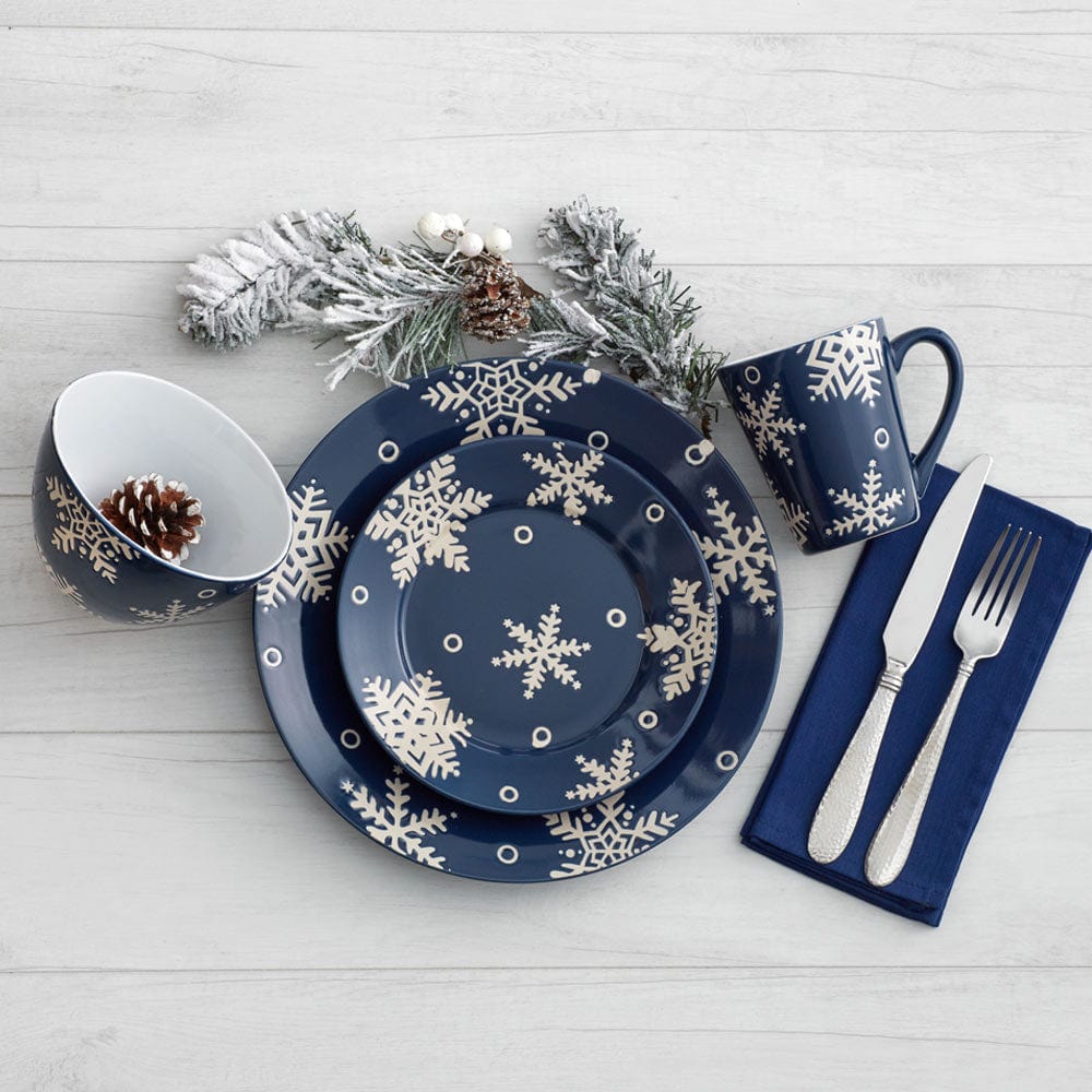 Snow Flurry navy dinner plates with white snowflake pattern arranged with a matching bowl mug and silverware on a light wooden table