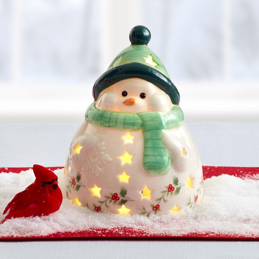 Winterberry Jolly Snowman ceramic lantern with star cutouts glowing and a red cardinal on snow.